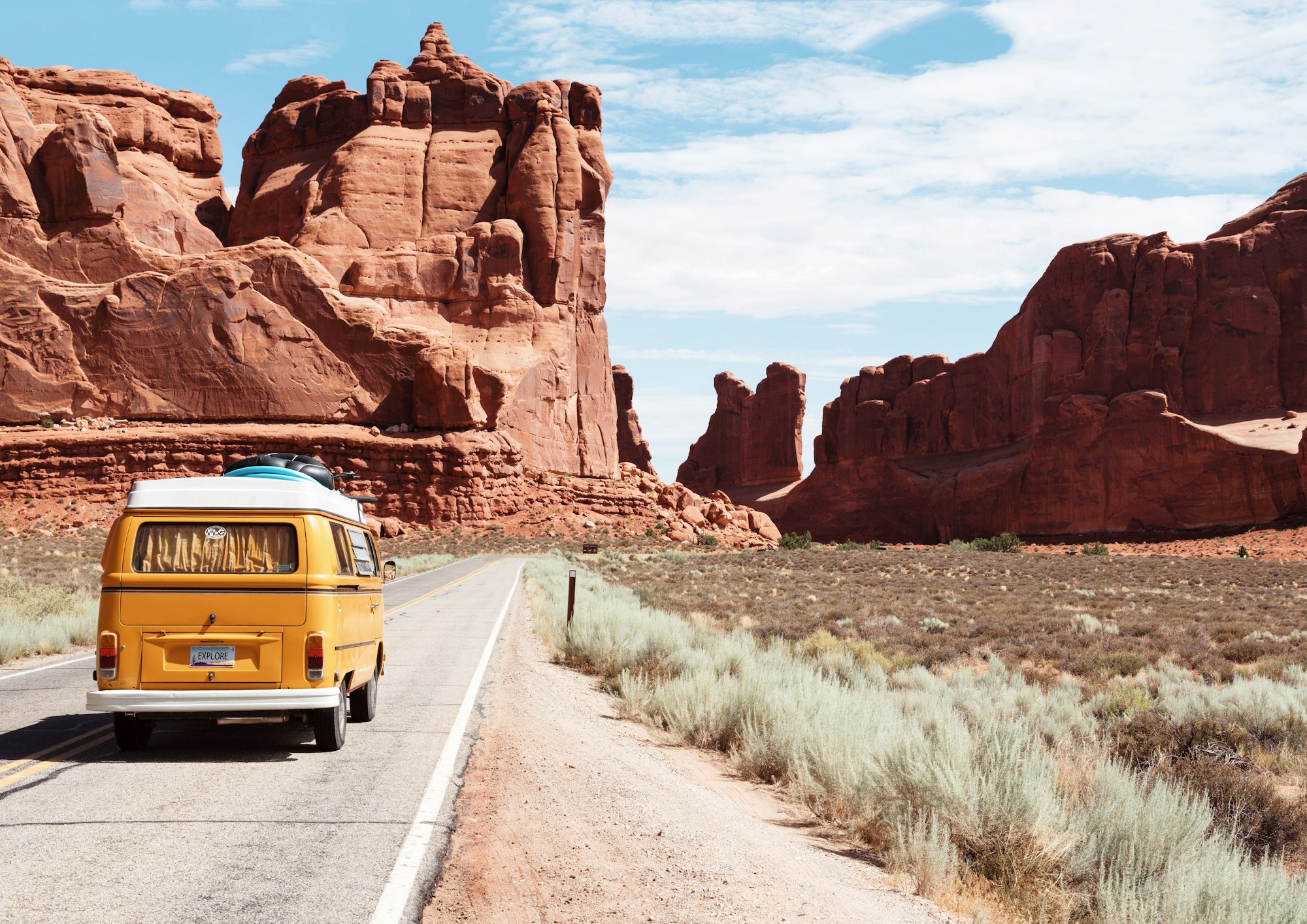 A camper van on an open road winding through dramatic scenery